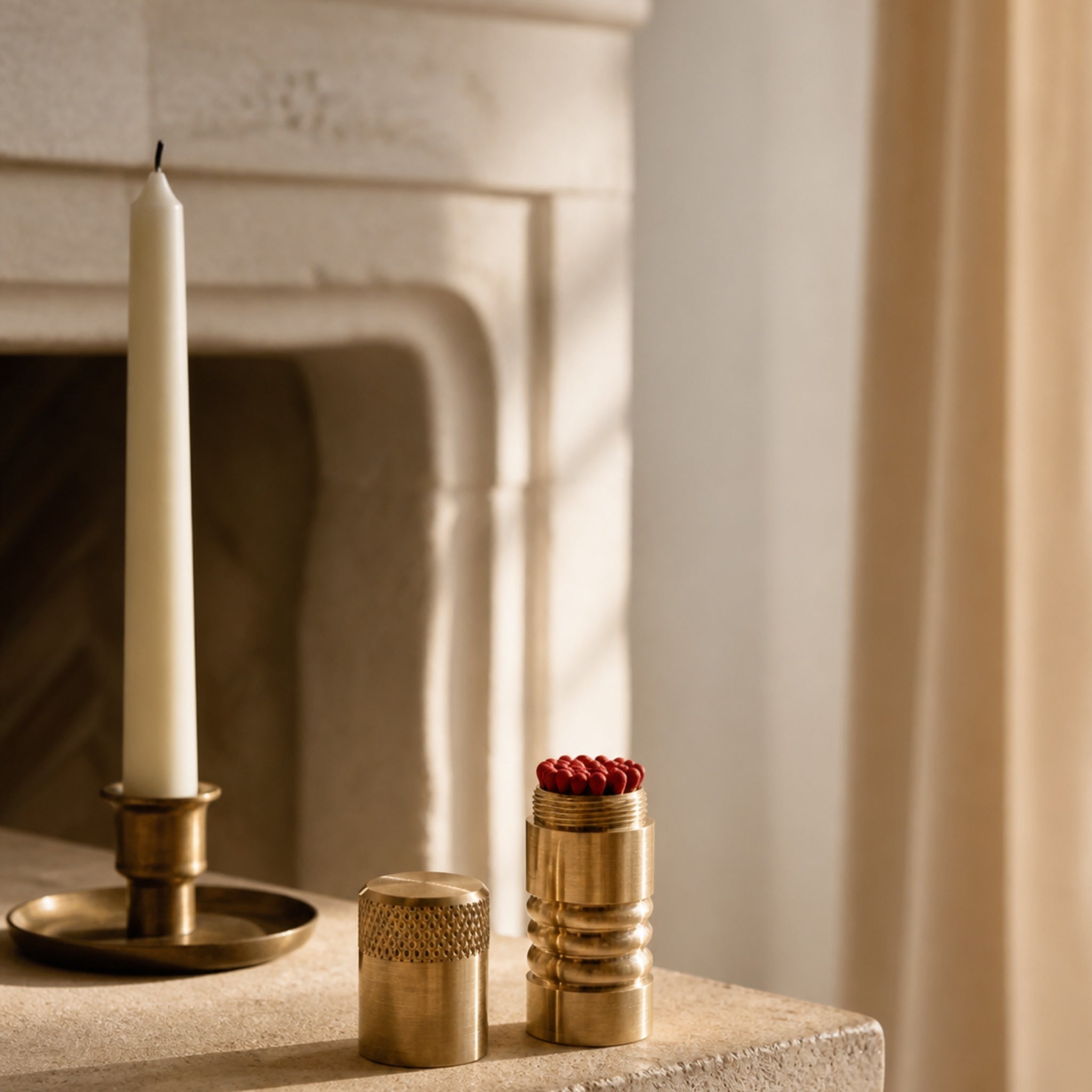 Şömine önünde pirinç kibritlik ve mumdan oluşan sıcak yaşam alanı düzenlemesi